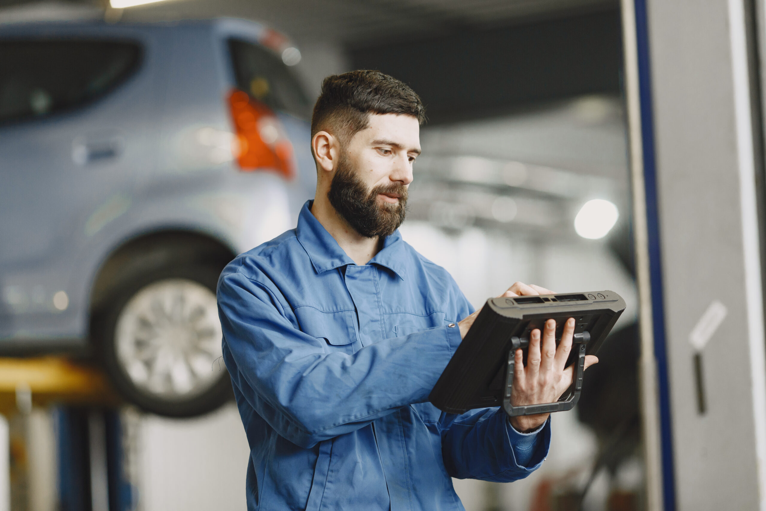 Сar mechanic with a tablet near car in work clothes