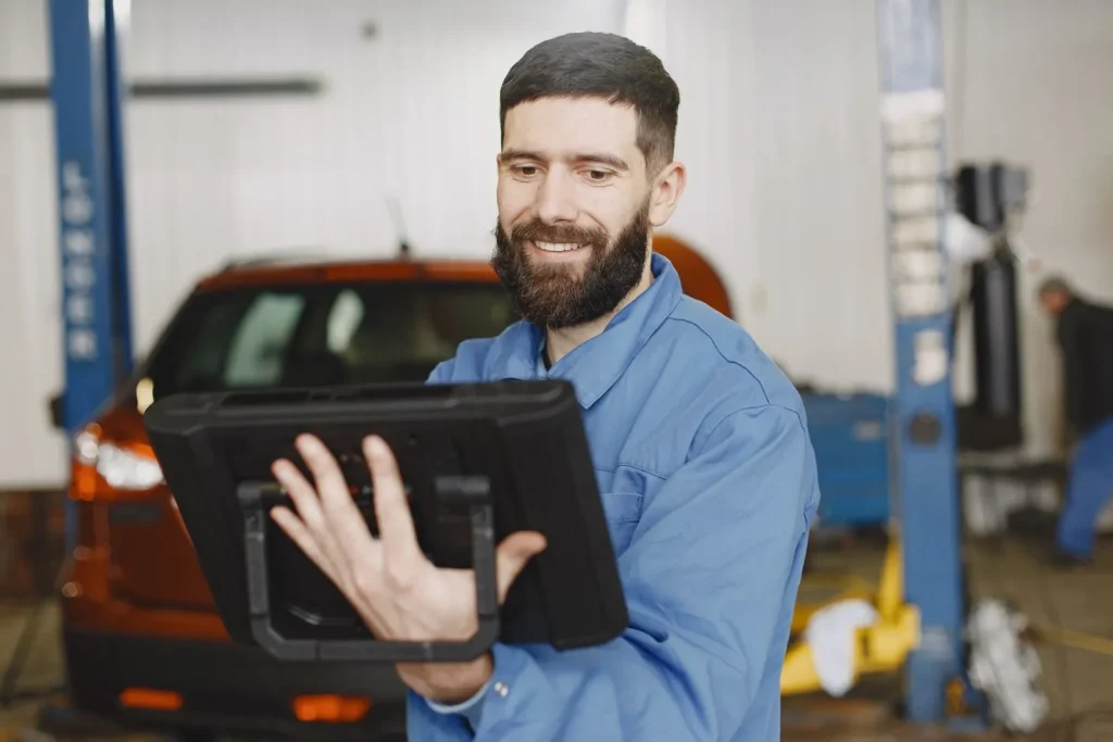Mechanic using a tablet to inspect a car in a workshop