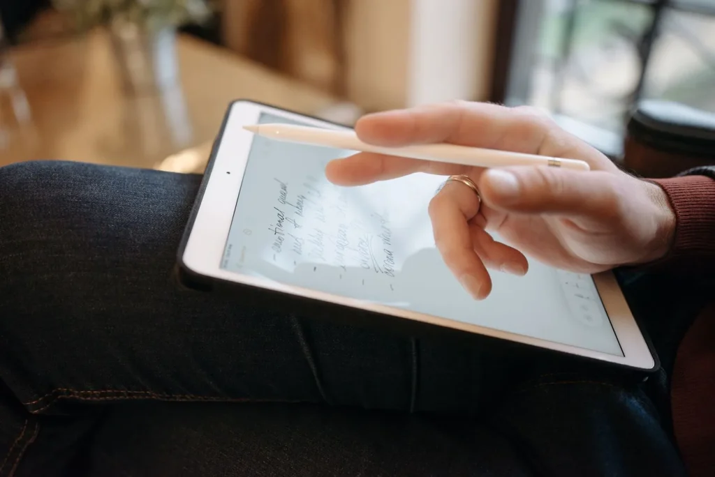 Hand with a stylus writing on a tablet