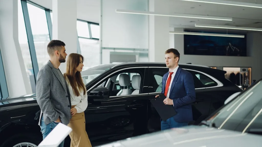 Salesperson helping a couple choose a car in a showroom