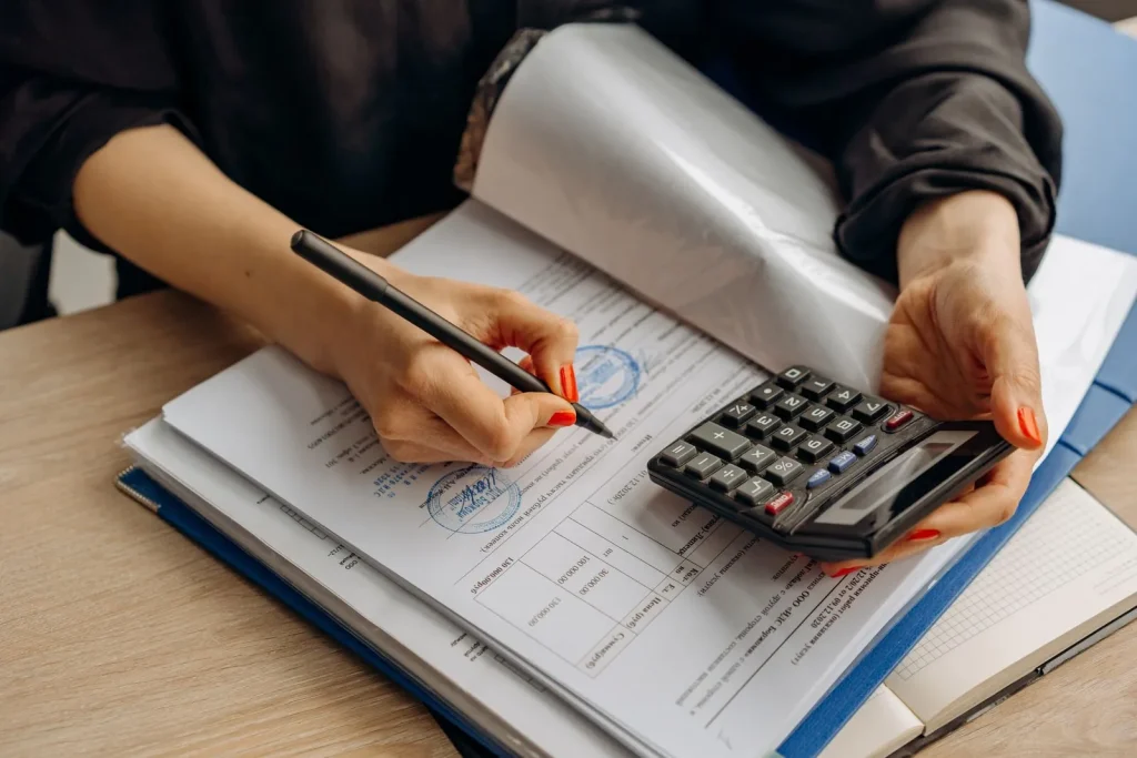 Accountant with a calculator signing paperwork