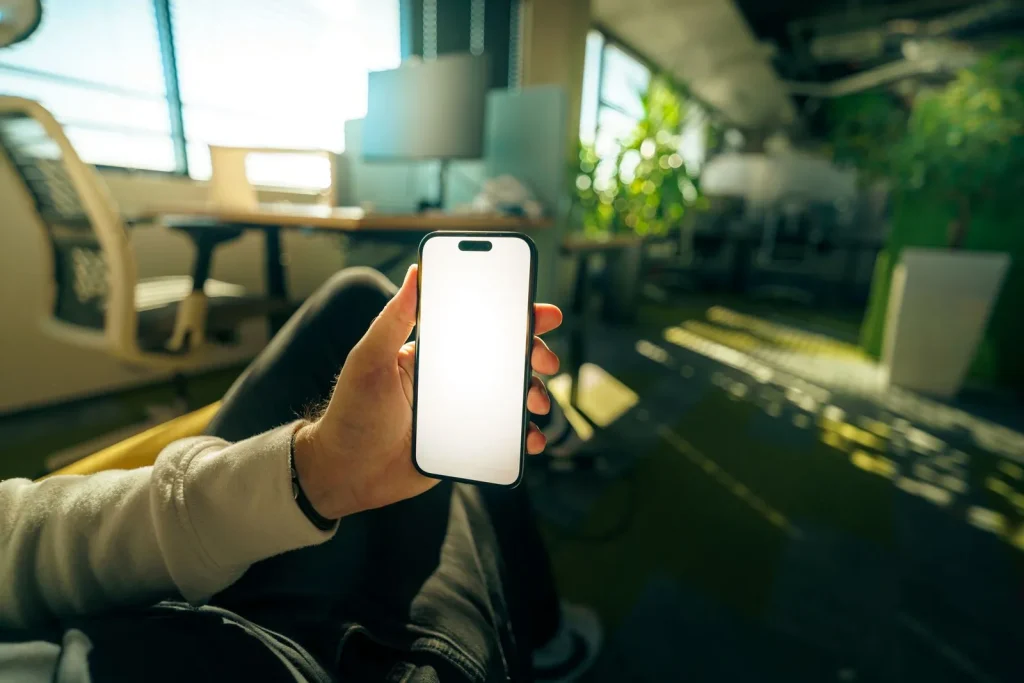 Hand holding a smartphone in an office