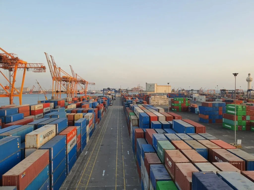 Container port with stacked cargo containers and cranes at sunrise