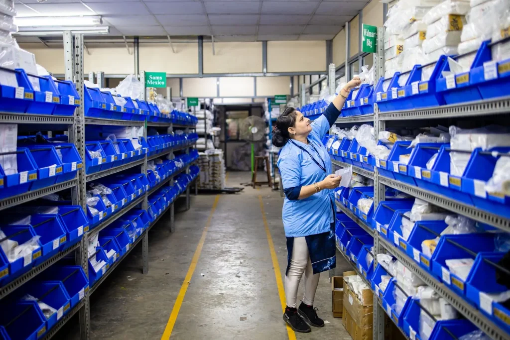 Worker checking stock in a parts aisle with labelled bins