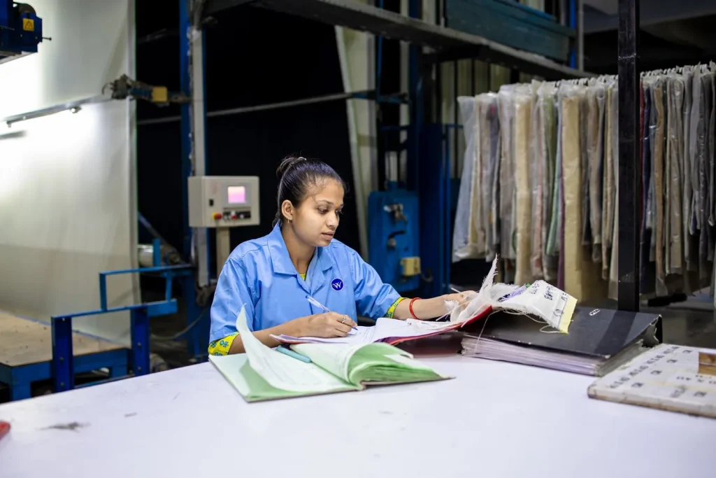 Factory worker checking paper quality records and forms at a workstation