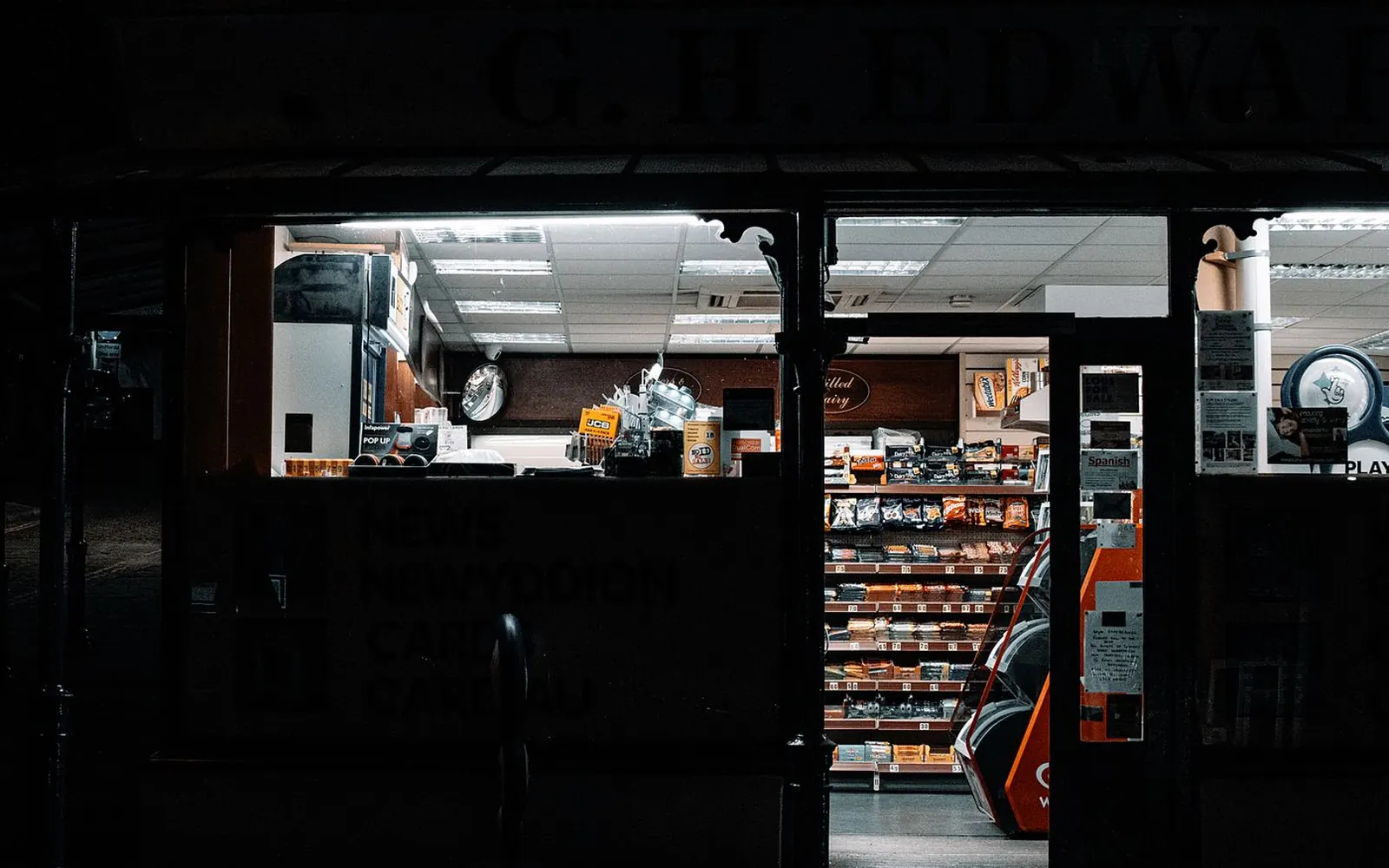 A convenience store lit up at night, shelves visible through the open door